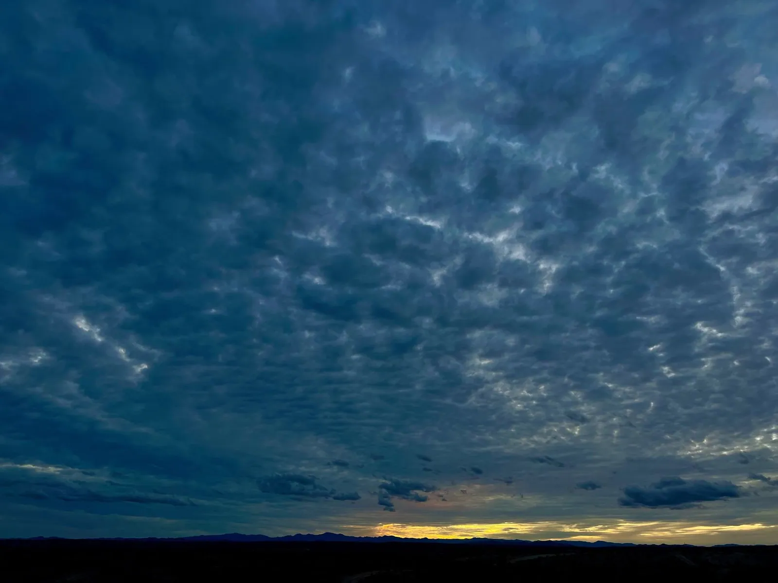 Sunset with a silhouetted mountain range and dramatic spirally type cloud situation.
