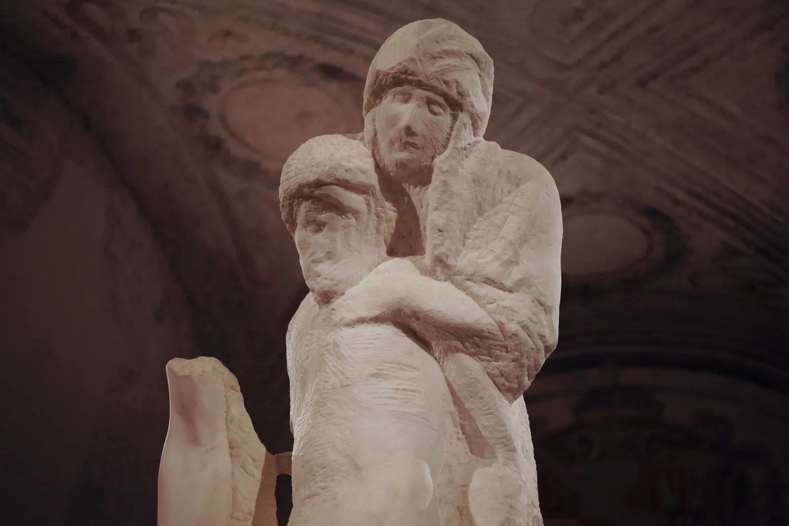 A stone sculpture of a mother standing above holding the limp form of her dead child.