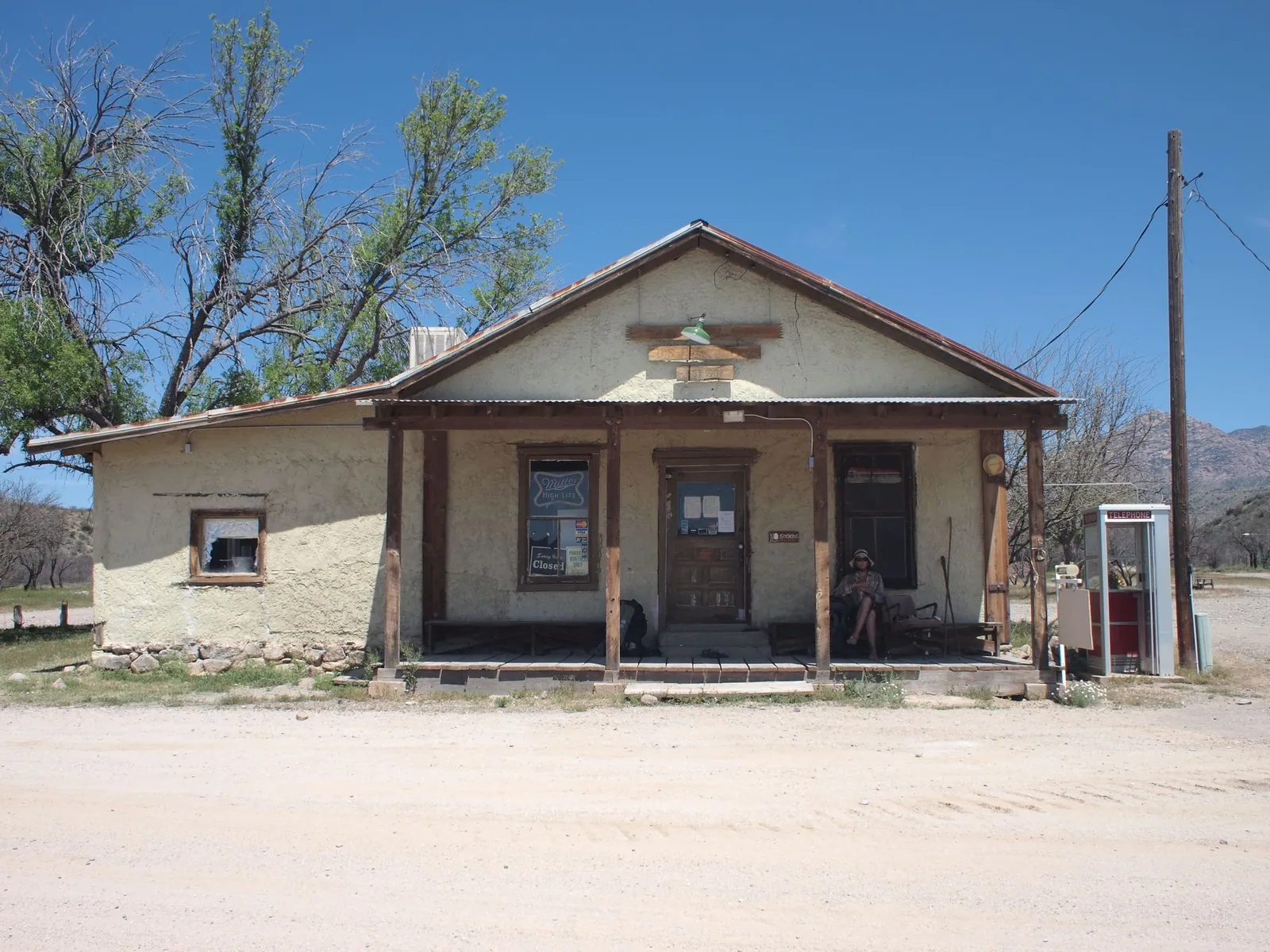 An old white plaster general store with wooden front porch in the desert.