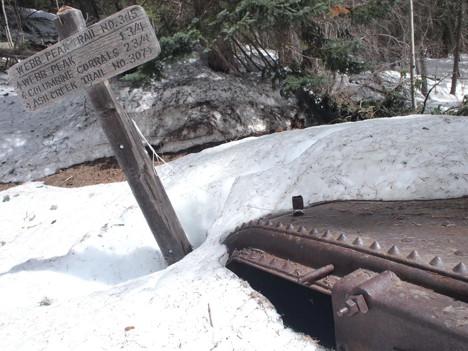 A wooden trailing and old rust metal remnants buried in snow