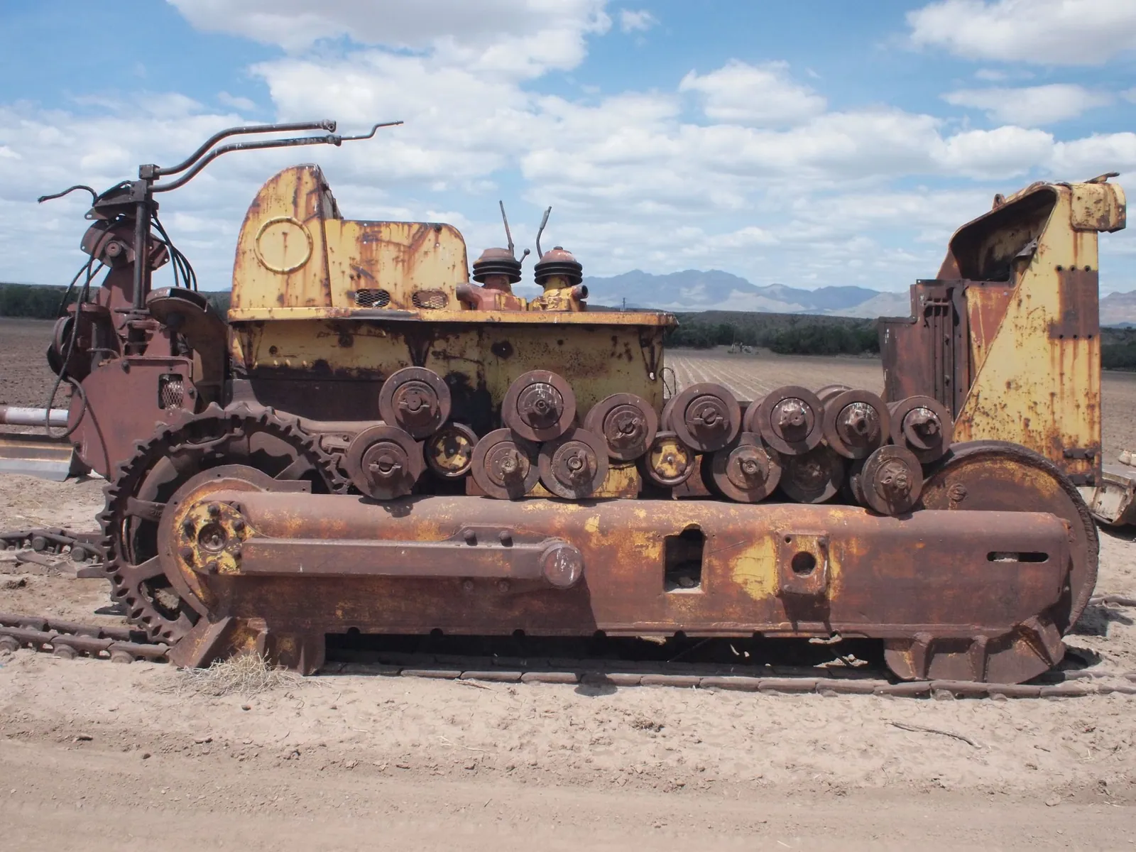 a yellow and rusty large machine in a cotton field